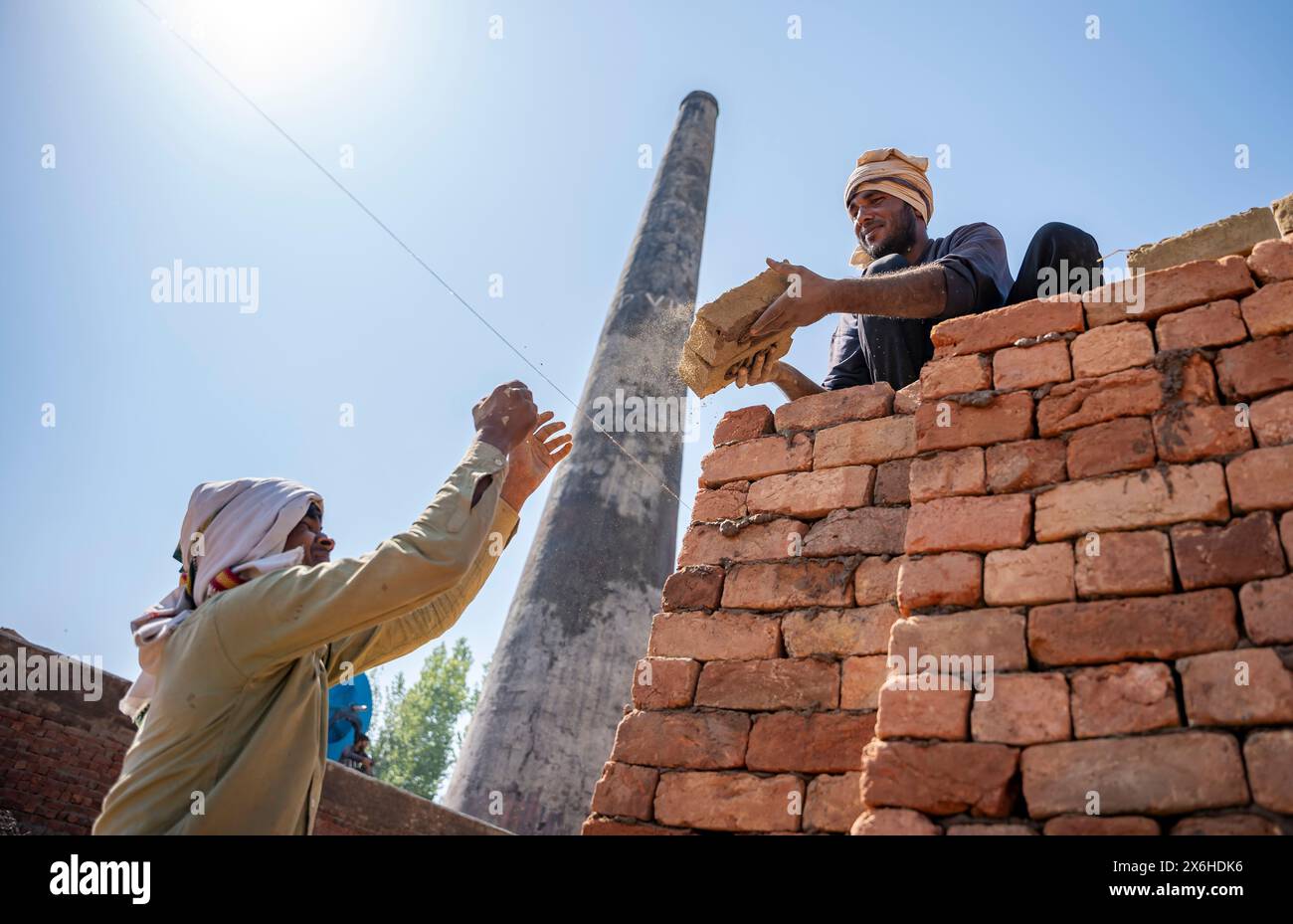 Nonlocal labourers load bricks on the kiln in Budgam. The substantial