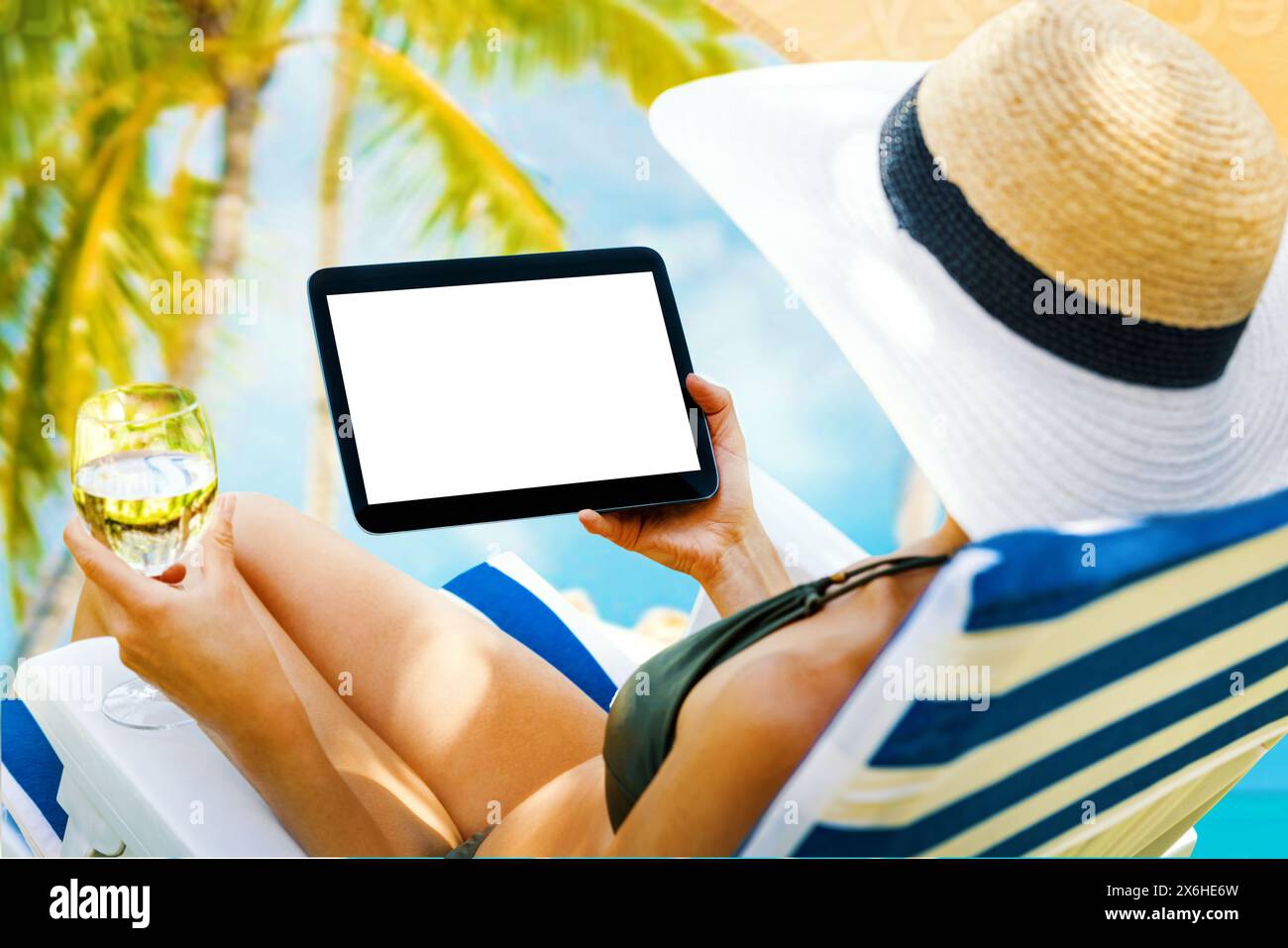 woman holding digital tablet with blank screen while laying down on beach chair at resort. mockup Stock Photo