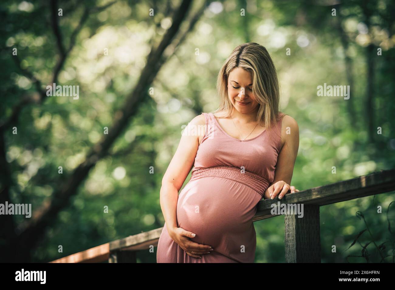 Pregnant woman posing in a green garden Stock Photo - Alamy