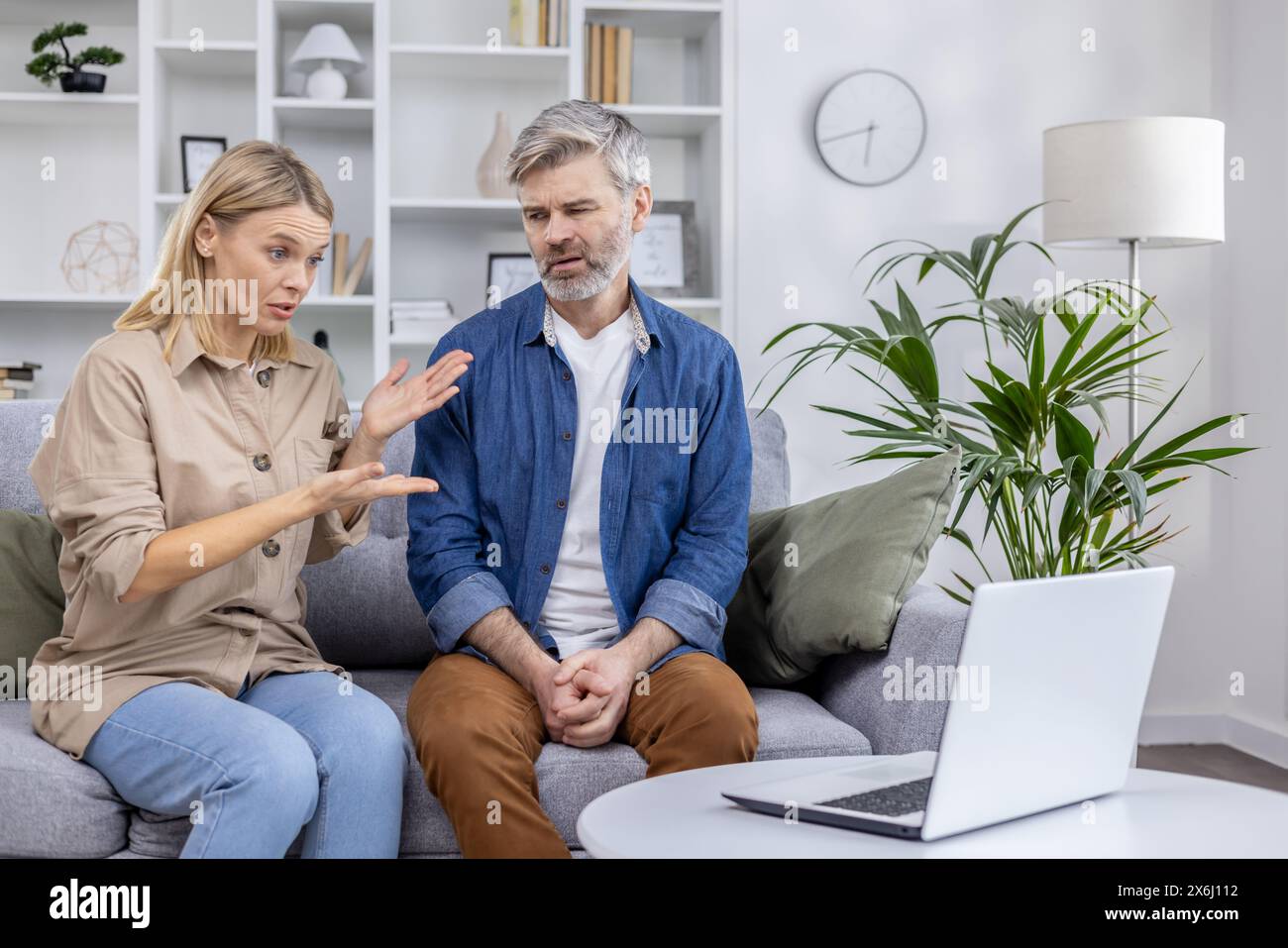 Couple sits on the couch having a video call consultation with a psychologist, discussing family conflict and therapy Stock Photo