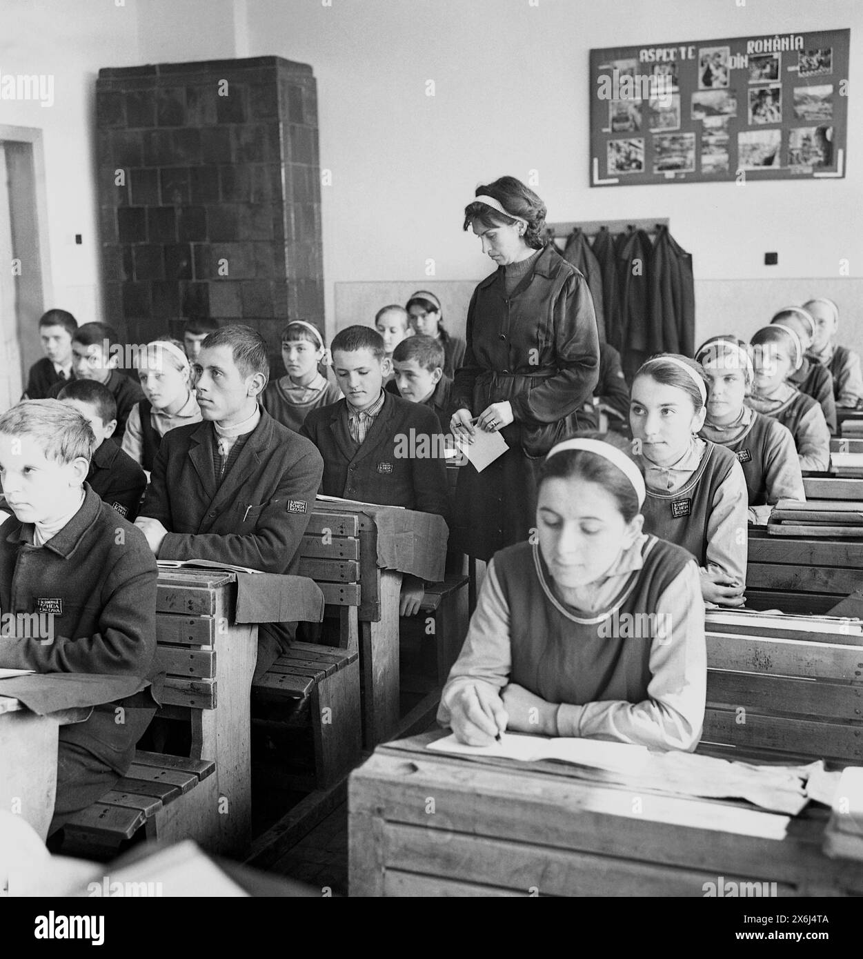 Șcheia, Suceava County, Socialist Republic of Romania  in the 1970s. 'Pioneers', students in middle school wearing the standardized communist uniform, during a class. This rural school had simple wooden furniture and a large terracotta wood stove for heating. Stock Photo