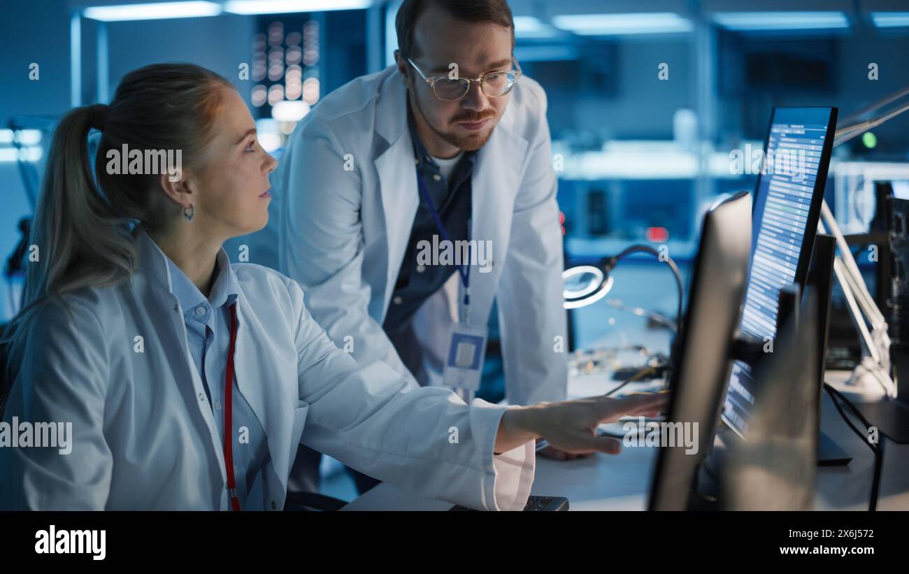 Electronics Research, Development Facility: Engineer Project Manager Consults Scientist working on Computer. Diverse Team of Professionals Design Silicon Microchip, Semiconductors, Motherboard Stock Photo