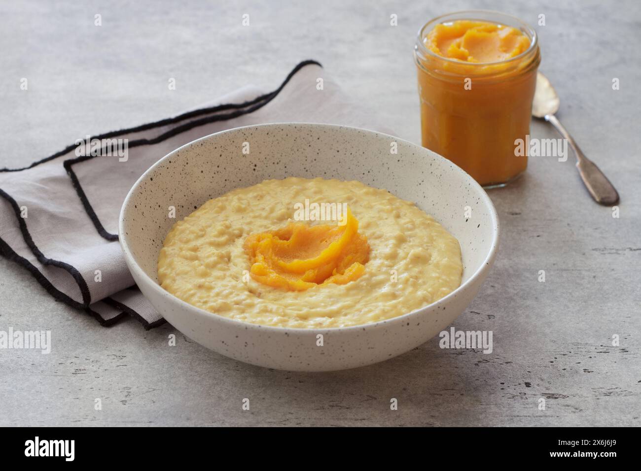 Bowl of oatmeal with pumpkin on a gray textured background. Delicious healthy homemade breakfast Stock Photo
