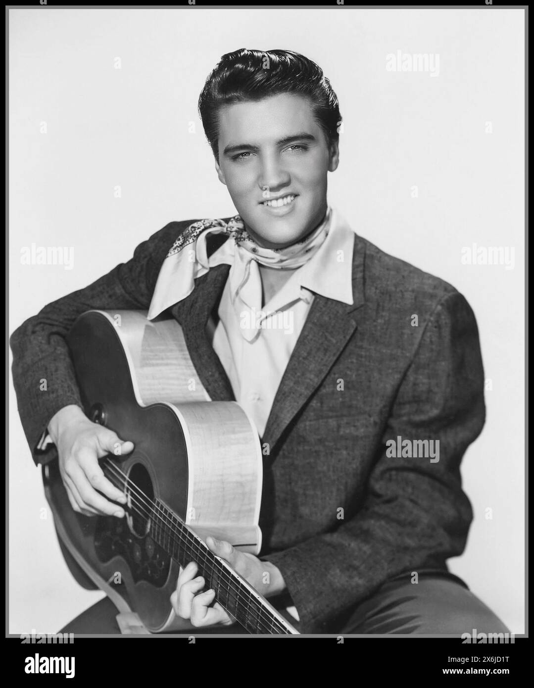 Elvis Presley 1958 posing for a studio promotional portrait on white background with his guitar. ELVIS PRESLEY '50's Vintage 1950's Hollywood film studio press promotional portrait still of Elvis Presley 'The King' Stock Photo