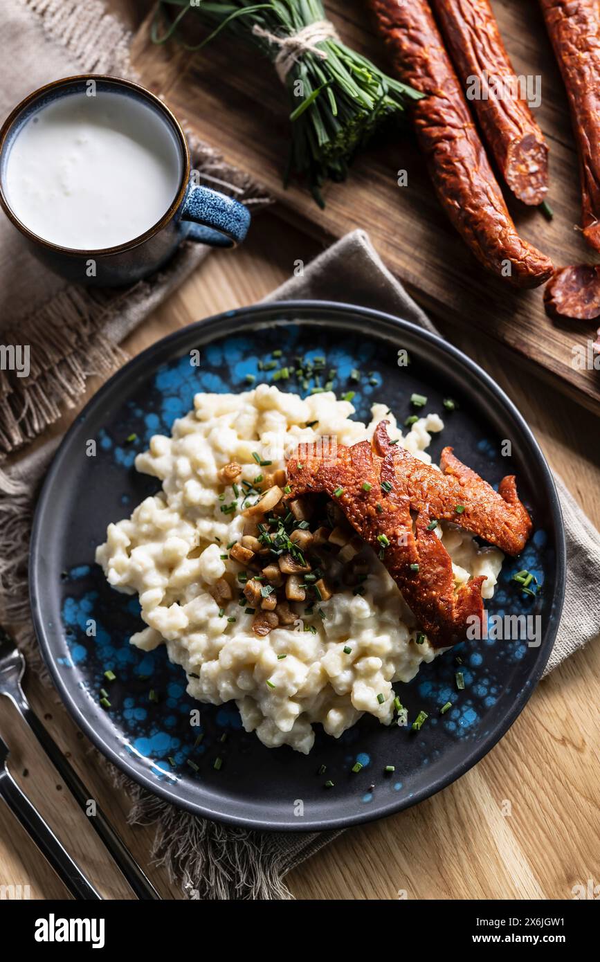 Halusky, Slovak potato gnocchi with sheep cheese bryndza, fried bacon, sausage and chives Stock Photo