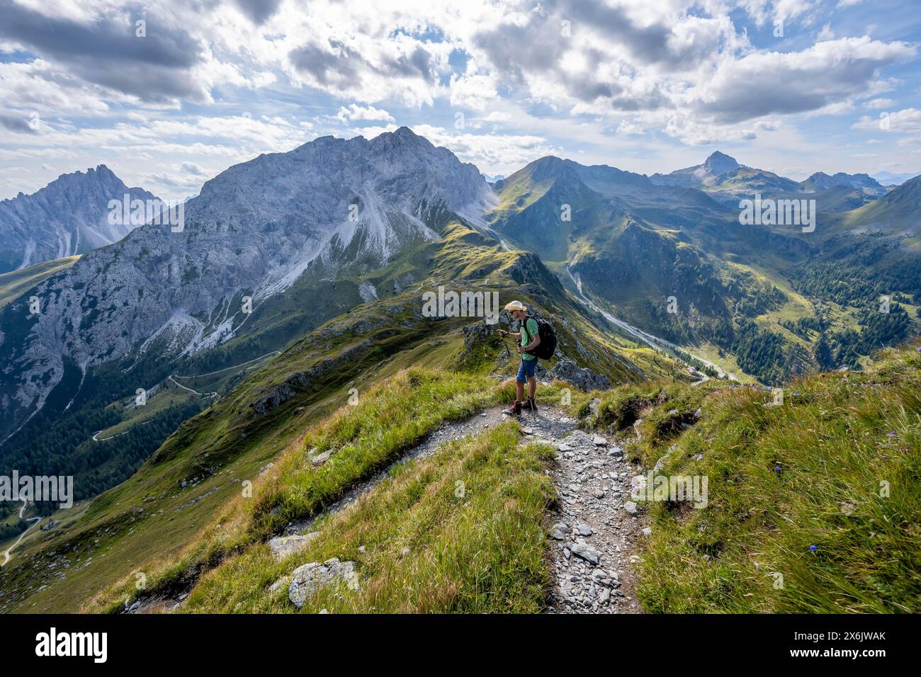 Mountaineer on a hiking trail on a grassy mountain ridge, idyllic ...