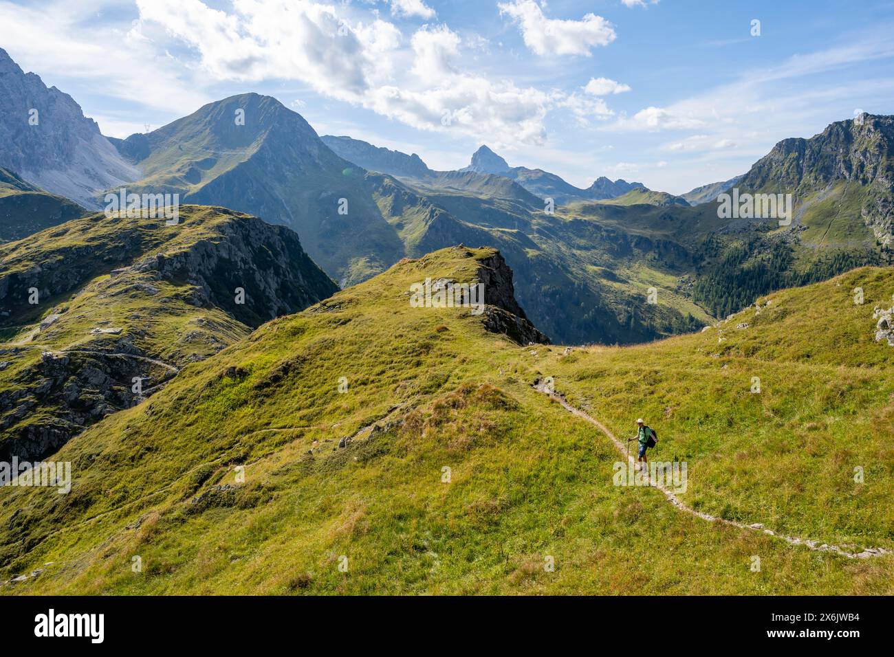 Mountaineer on a hiking trail on a grassy mountain ridge, idyllic ...