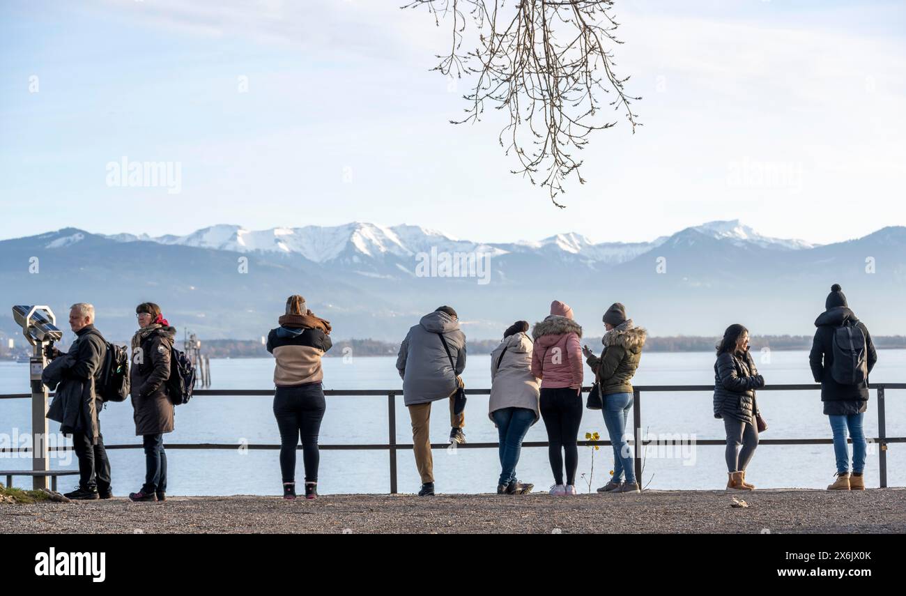 People enjoying the view of snow-covered mountain peaks on Lake Constance in winter, Lindau Island, Lake Constance, Bavaria, Germany Stock Photo