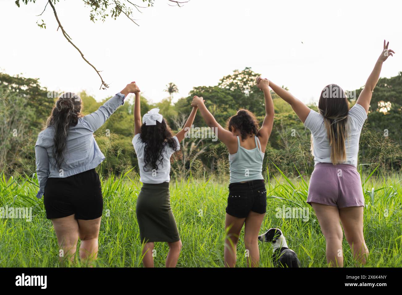 four Latina girls holding hands as they are lifted to the sky, celebrating their freedom and empowerment Stock Photo