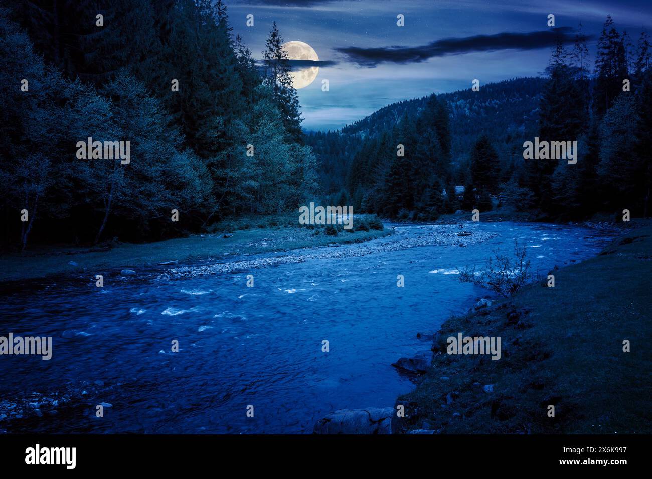 river flows through the valley of carpathian mountains at night. shallow water reveals stones. synevyr national park of ukraine in full moon light Stock Photo