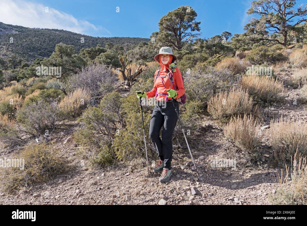Asian American woman in sun protection clothing hiking down Mount Stirling in Nevada Stock Photo