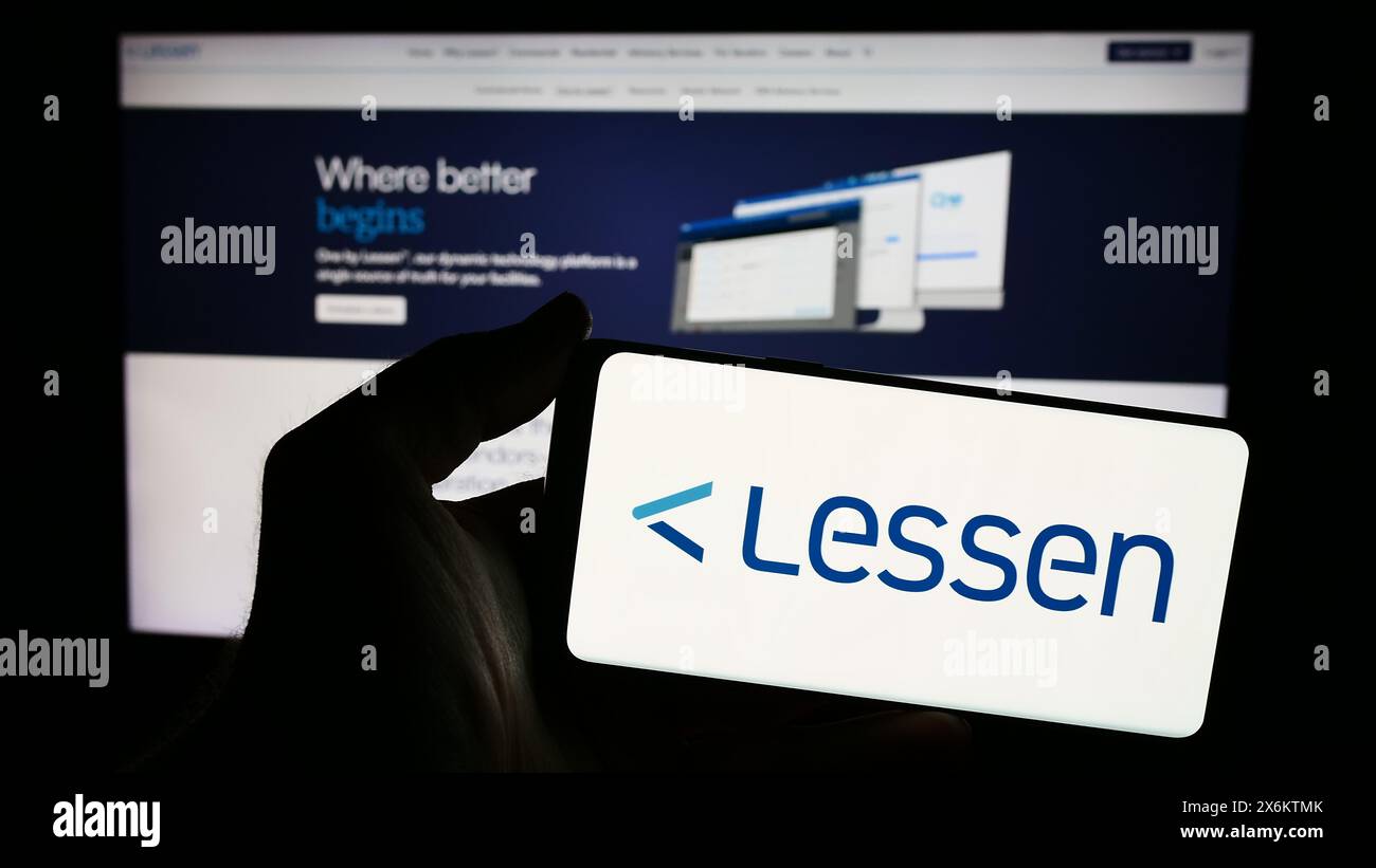 Person holding smartphone with logo of US property services marketplace company Lessen Inc. in front of website. Focus on phone display. Stock Photo