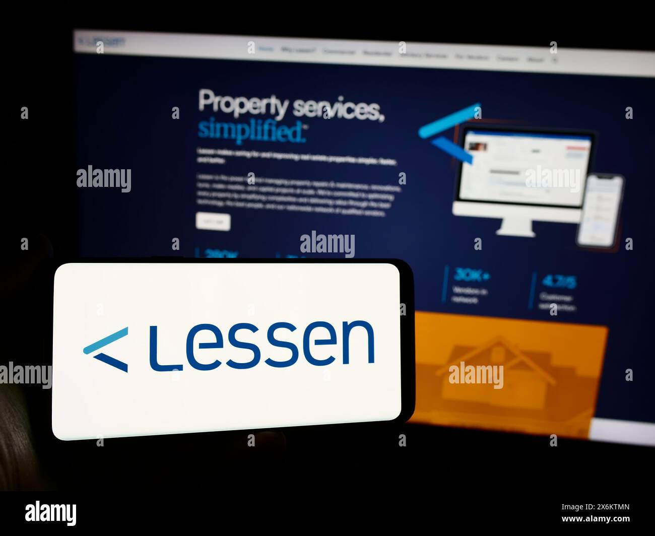 Person holding mobile phone with logo of American property services marketplace company Lessen Inc. in front of web page. Focus on phone display. Stock Photo