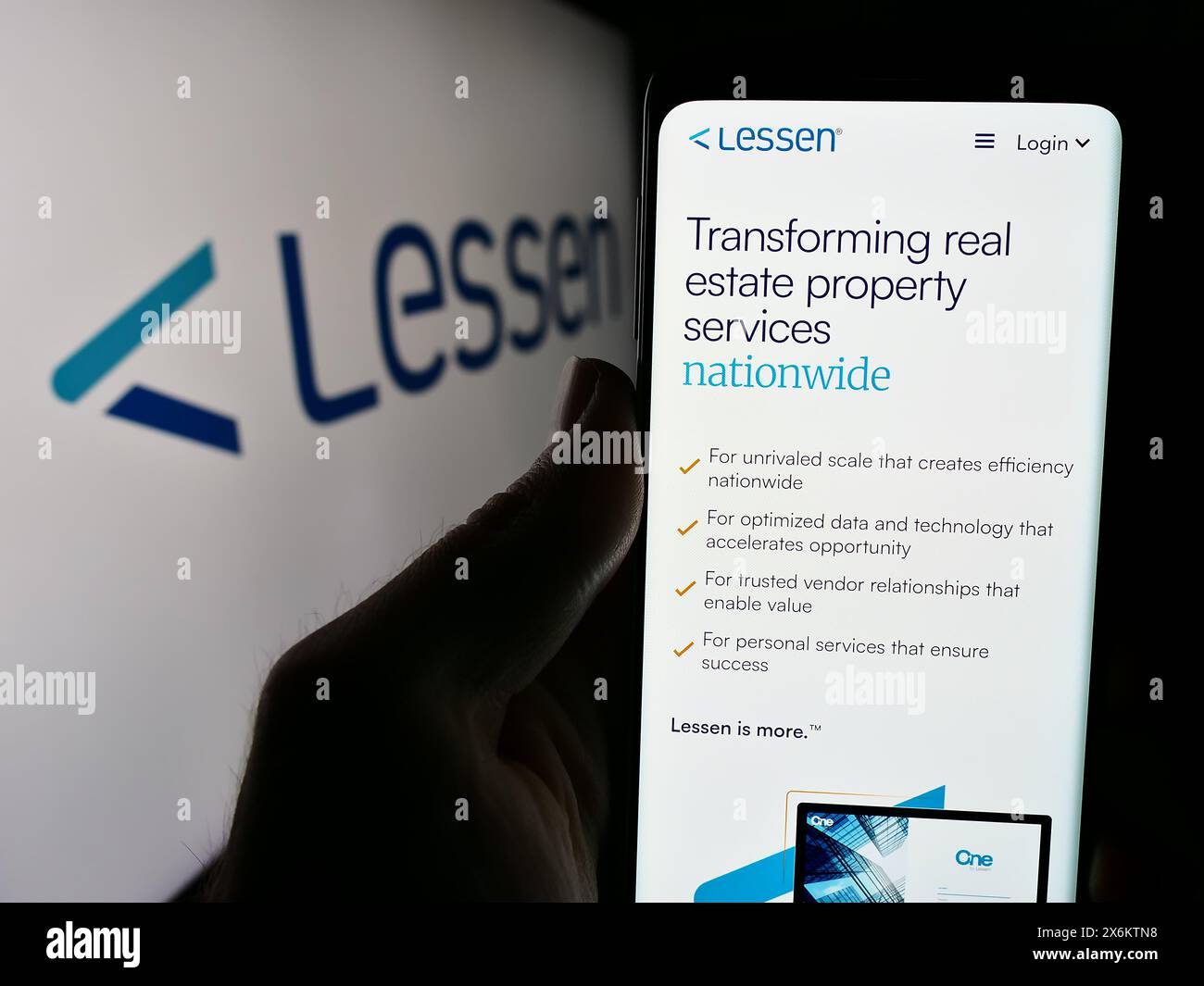 Person holding cellphone with webpage of US property services marketplace company Lessen Inc. in front of logo. Focus on center of phone display. Stock Photo