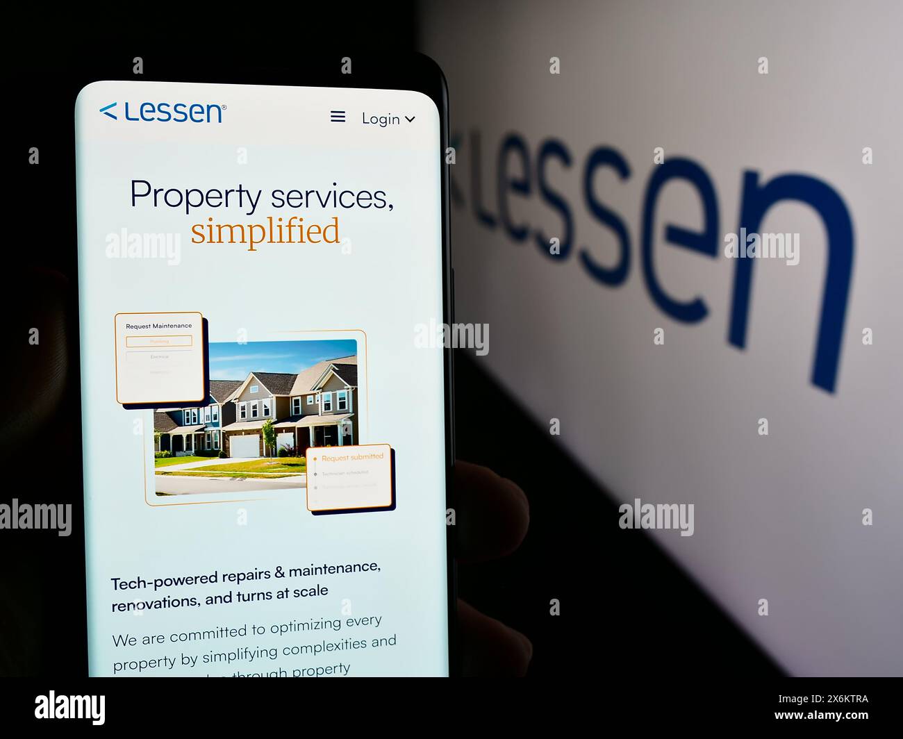 Person holding smartphone with web page of US property services marketplace company Lessen Inc. with logo. Focus on center of phone display. Stock Photo