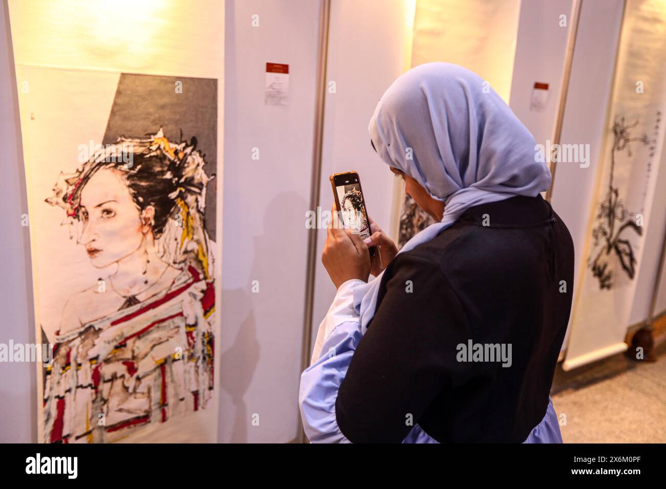 Cairo, Egypt. 14th May, 2024. A visitor films a painting at 'the Yellow River Civilization Embracing the Egyptian Civilization' exhibition in Cairo, Egypt, on May 14, 2024. From roaring tigers to delicate purple flowers, a fresh exhibition has captivated visitors in Cairo with works by artists from east China's Shandong Province. Organized by Shandong Painting Academy, 'the Yellow River Civilization Embracing the Egyptian Civilization' exhibition was unveiled on Tuesday at the China Cultural Center in Cairo. Credit: Ahmed Gomaa/Xinhua/Alamy Live News Stock Photo
