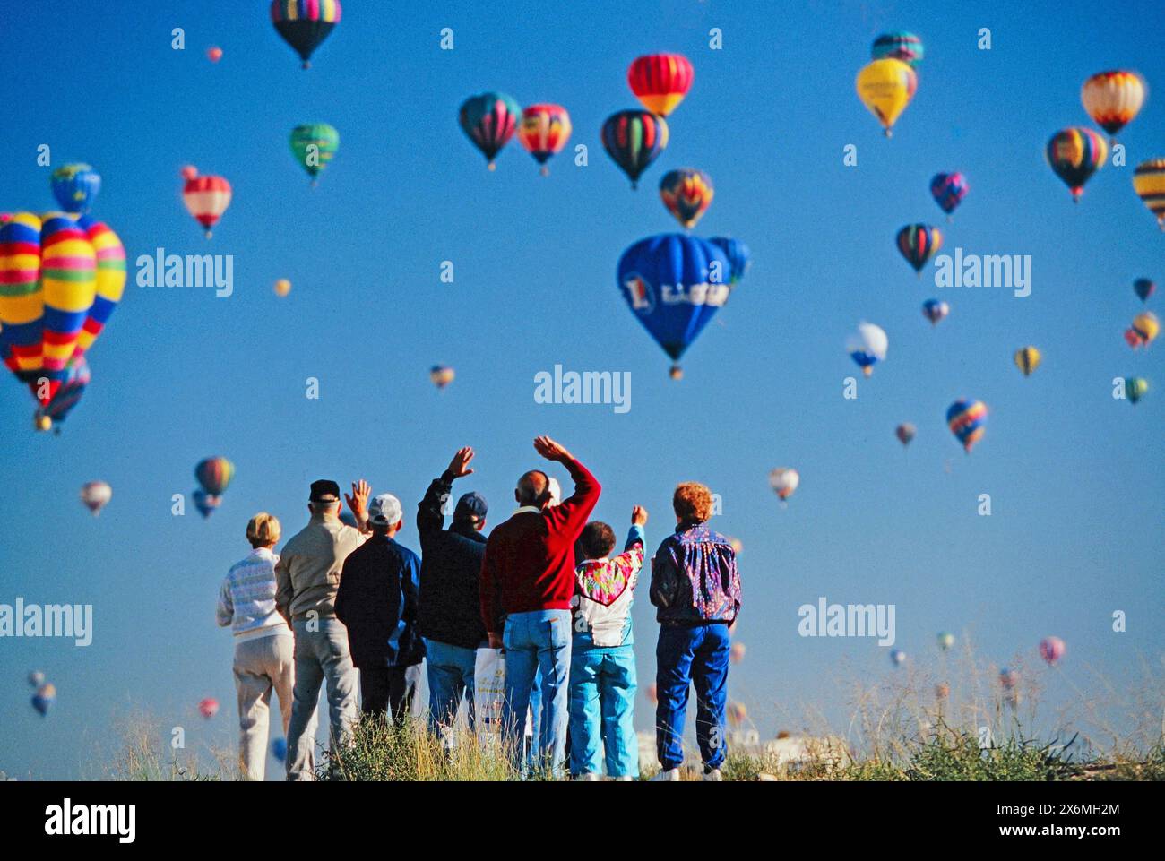 colorful hot air balloons drift through the sky at the Albuquerque balloon festival. Excitement and wonder evident on their faces as they observe the Stock Photo
