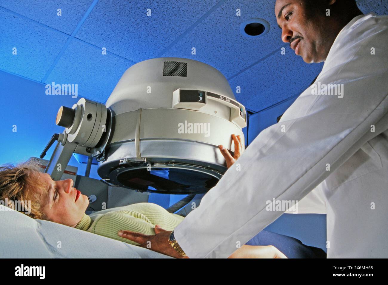 A doctor in medical attire is preparing a woman for a diagnostic procedure. The doctor appears focused as they assess the patients condition and provi Stock Photo