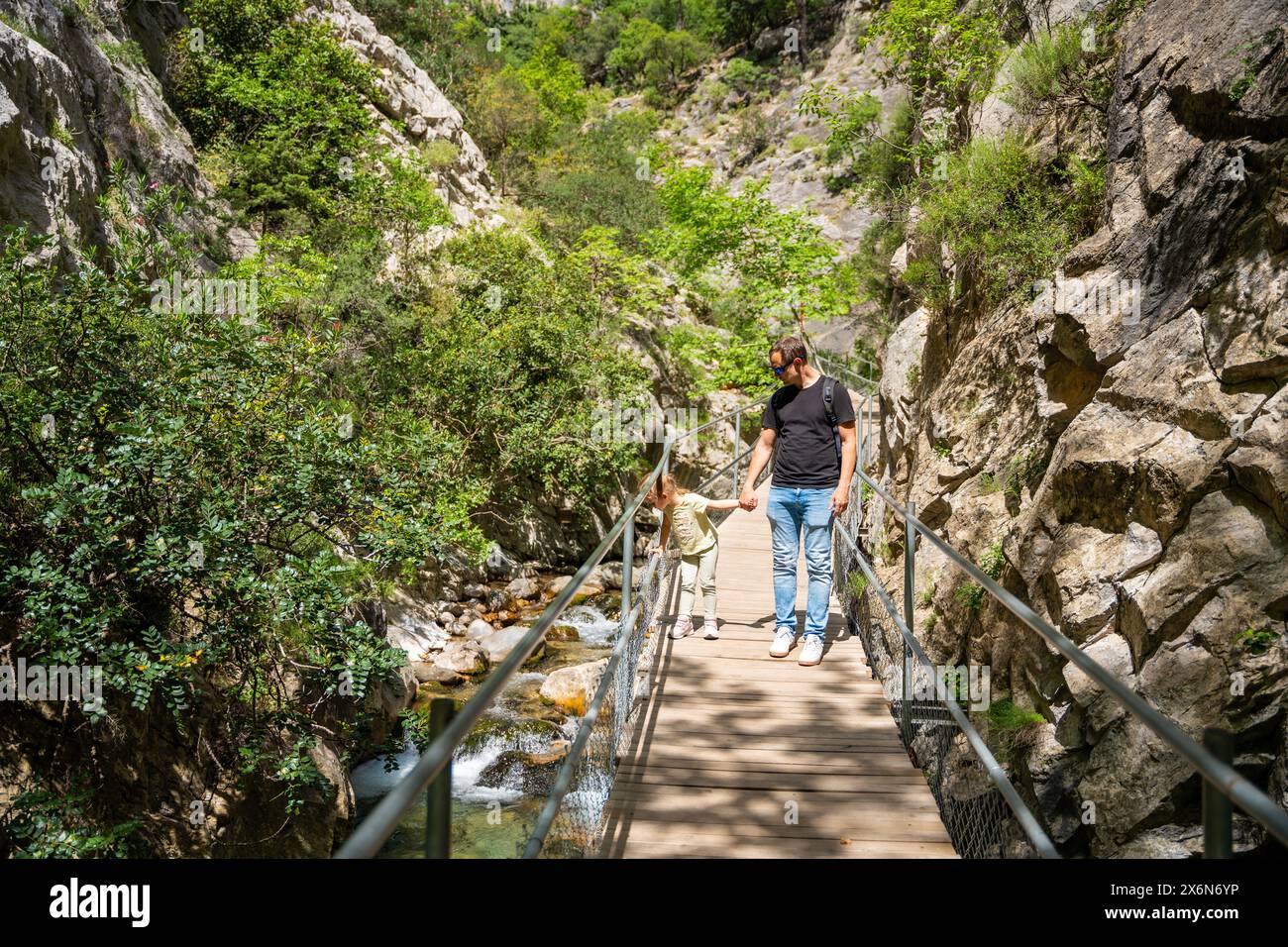 Father With Little Girl Hiking In Sapadere Canyon With Wooden Paths And father-with-little-girl-hiking-in-sapadere-canyon-with-wooden-paths-and