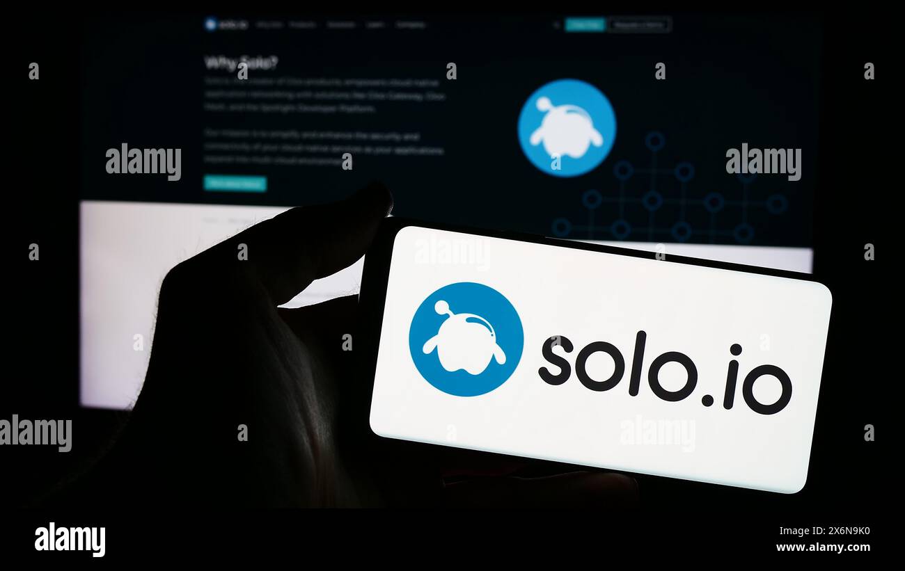 Person holding smartphone with logo of US networking platform company Solo.io Inc. in front of website. Focus on phone display. Stock Photo