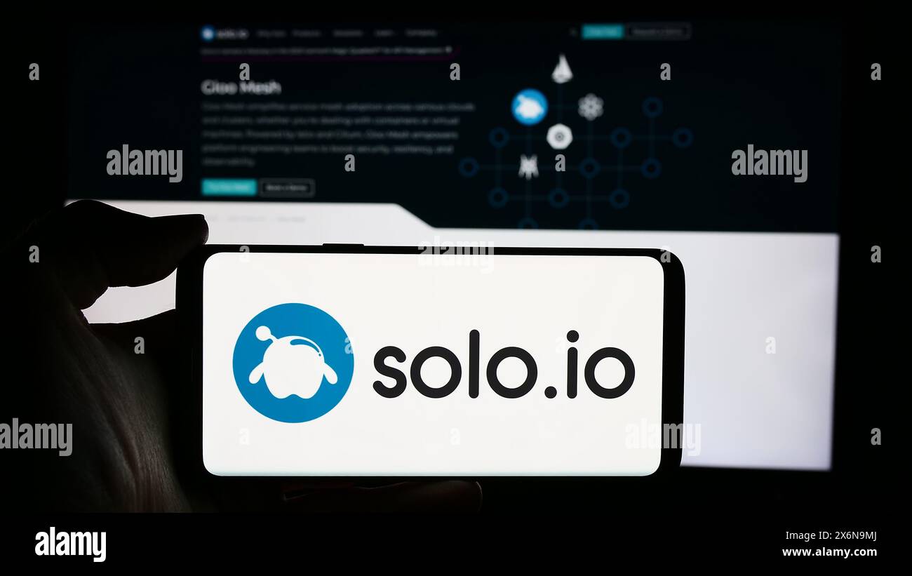 Person holding cellphone with logo of US networking platform company Solo.io Inc. in front of business webpage. Focus on phone display. Stock Photo