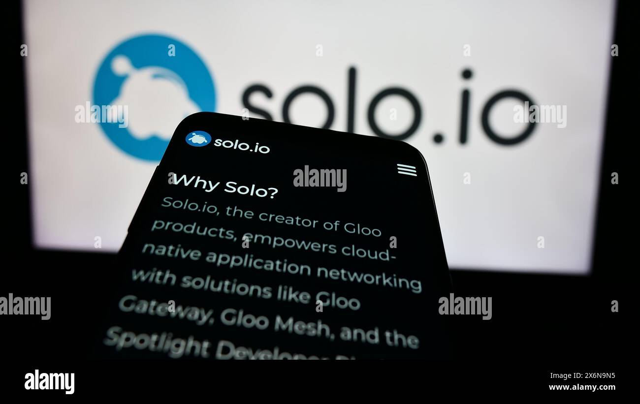 Smartphone with website of US networking platform company Solo.io Inc. in front of business logo. Focus on top-left of phone display. Stock Photo