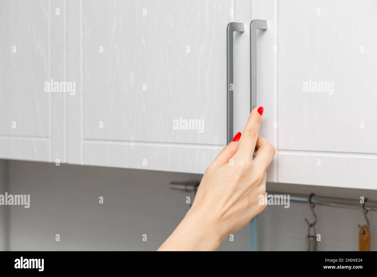 housewife opens kitchen wall cabinet, close-up. housewife opens a kitchen cabinet drawer with her hand. Stock Photo