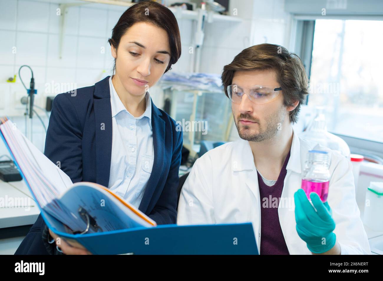 male lab worker making notes with female manager Stock Photo