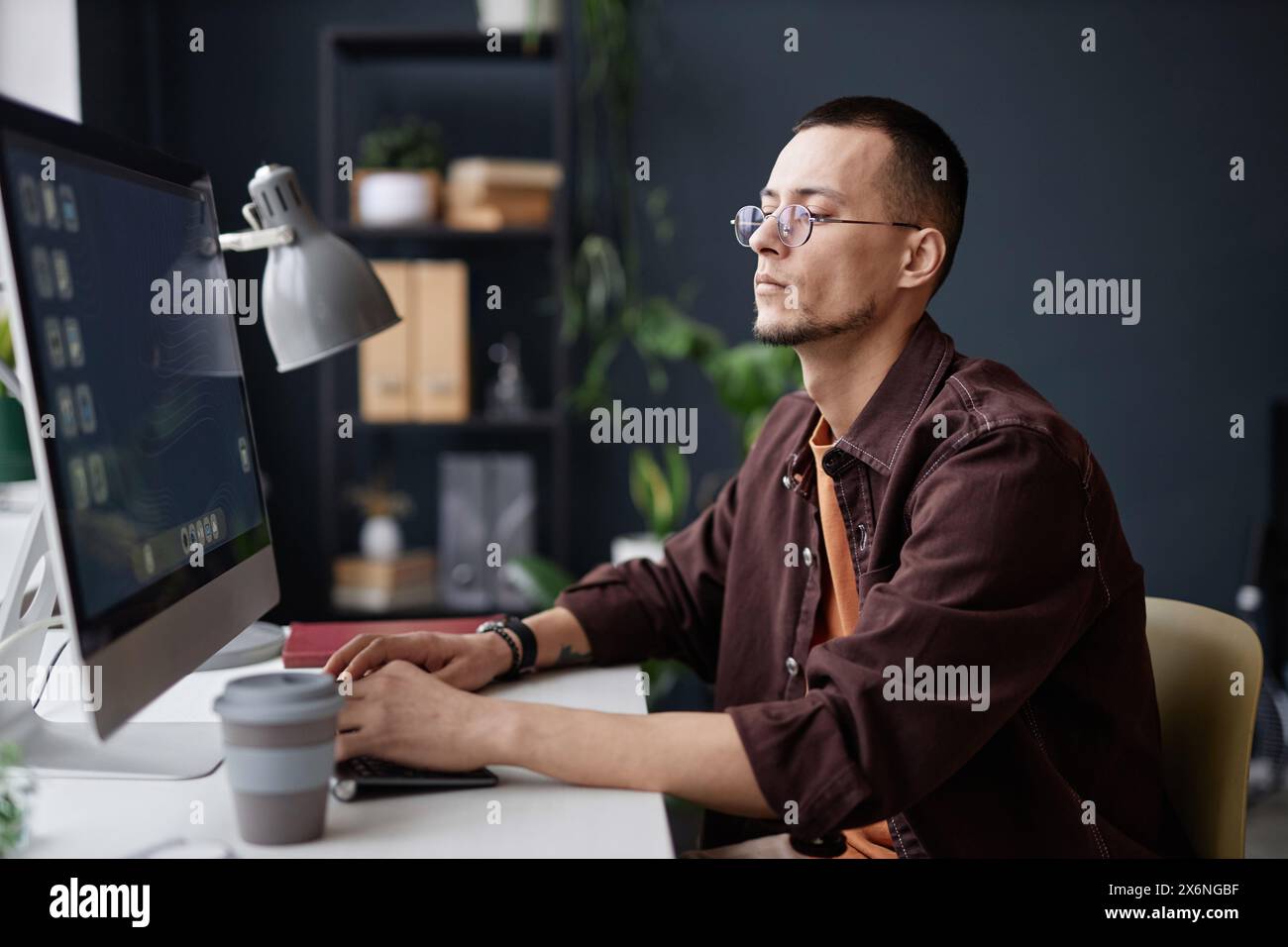 Minimal side view portrait of young Asian man using computer at ...