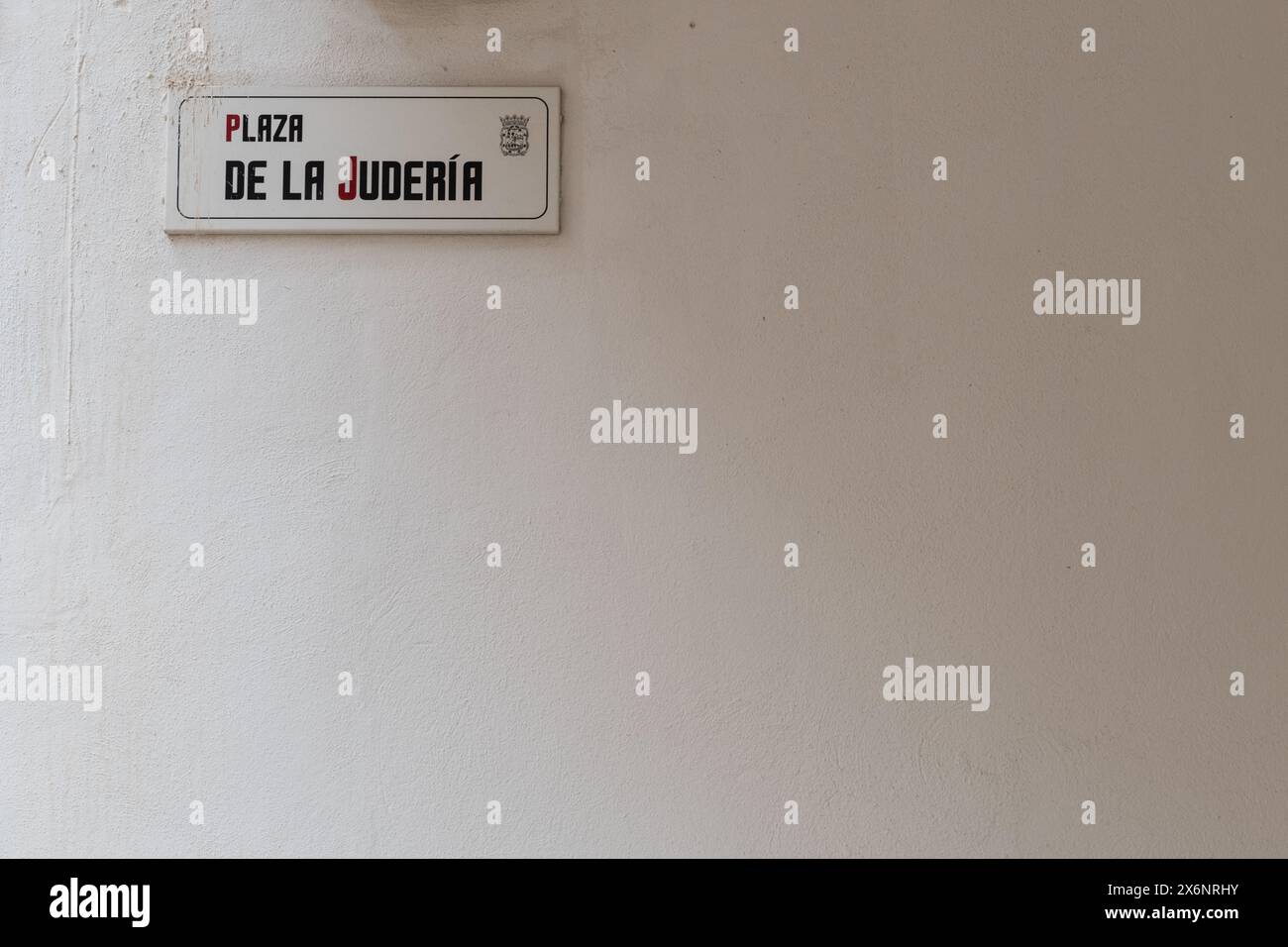 Street sign on a large, empty white wall in Malaga, southern Spain, which reads, in Spanish: Plaza of the Jews. Stock Photo