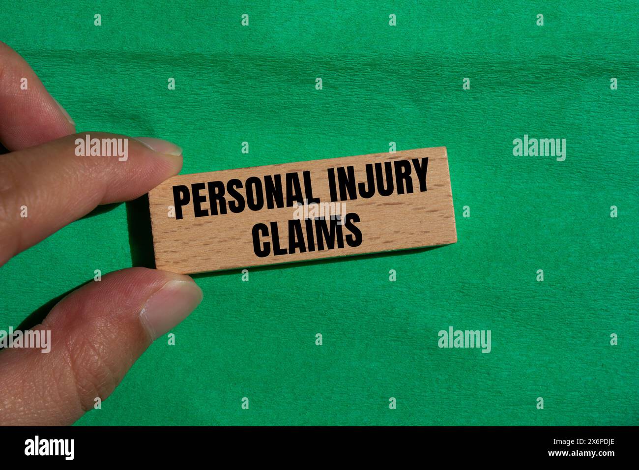 Personal injury claims written on wooden block with green background. Conceptual personal injury claims symbol. Copy space. Stock Photo
