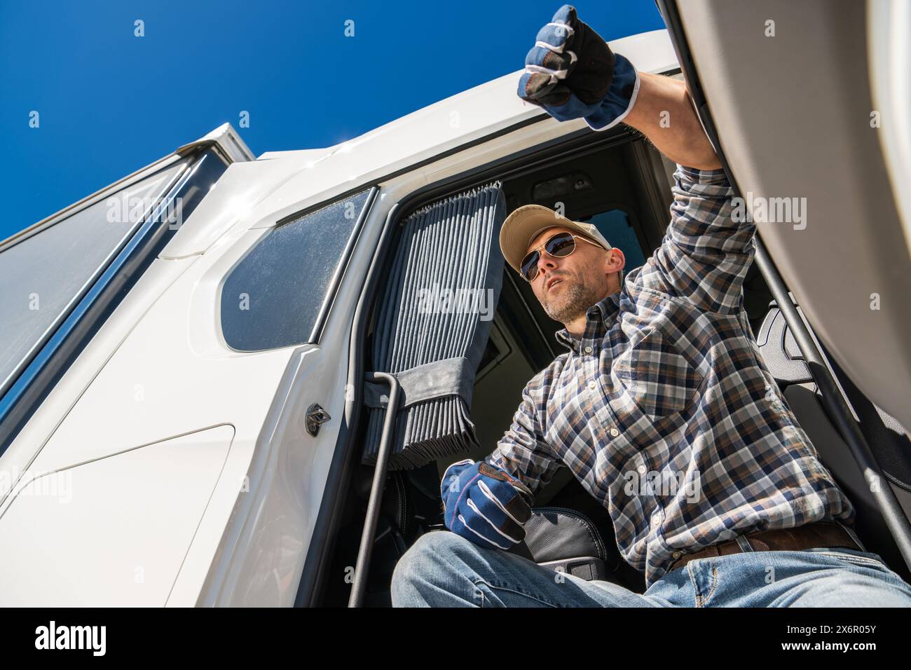 Trucker driver opening the door of a white truck to get fresh air. Stock Photo