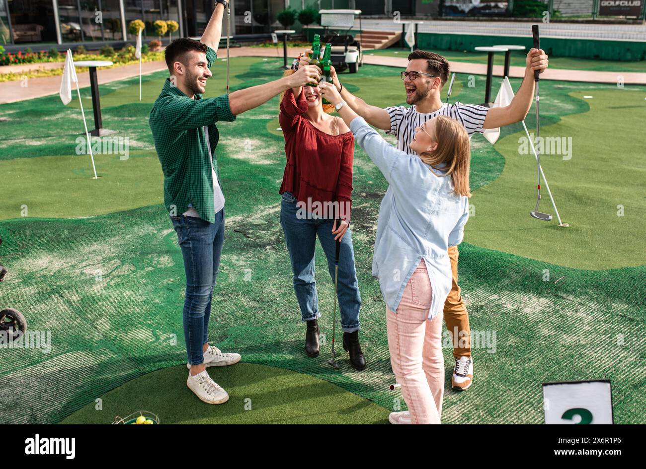 Group of smiling friends enjoying together playing mini golf in the city. Stock Photo