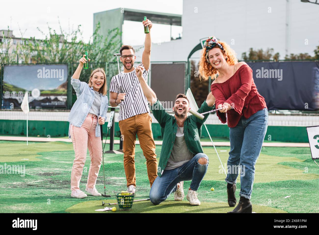 Group of smiling friends enjoying together playing mini golf in the city. Stock Photo
