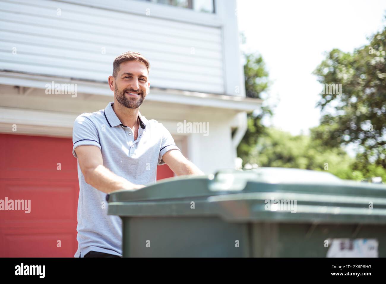 Caucasian Man is Walking Outside His House in Order to Take Out Trash Stock Photo