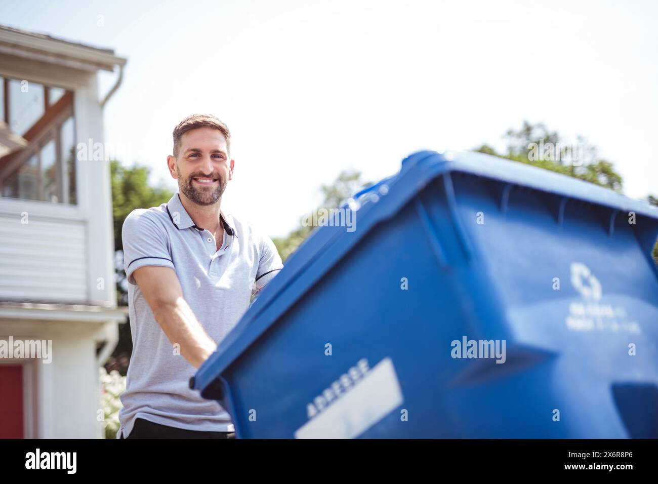Caucasian Man is Walking Outside His House in Order to Take Out recycling Stock Photo