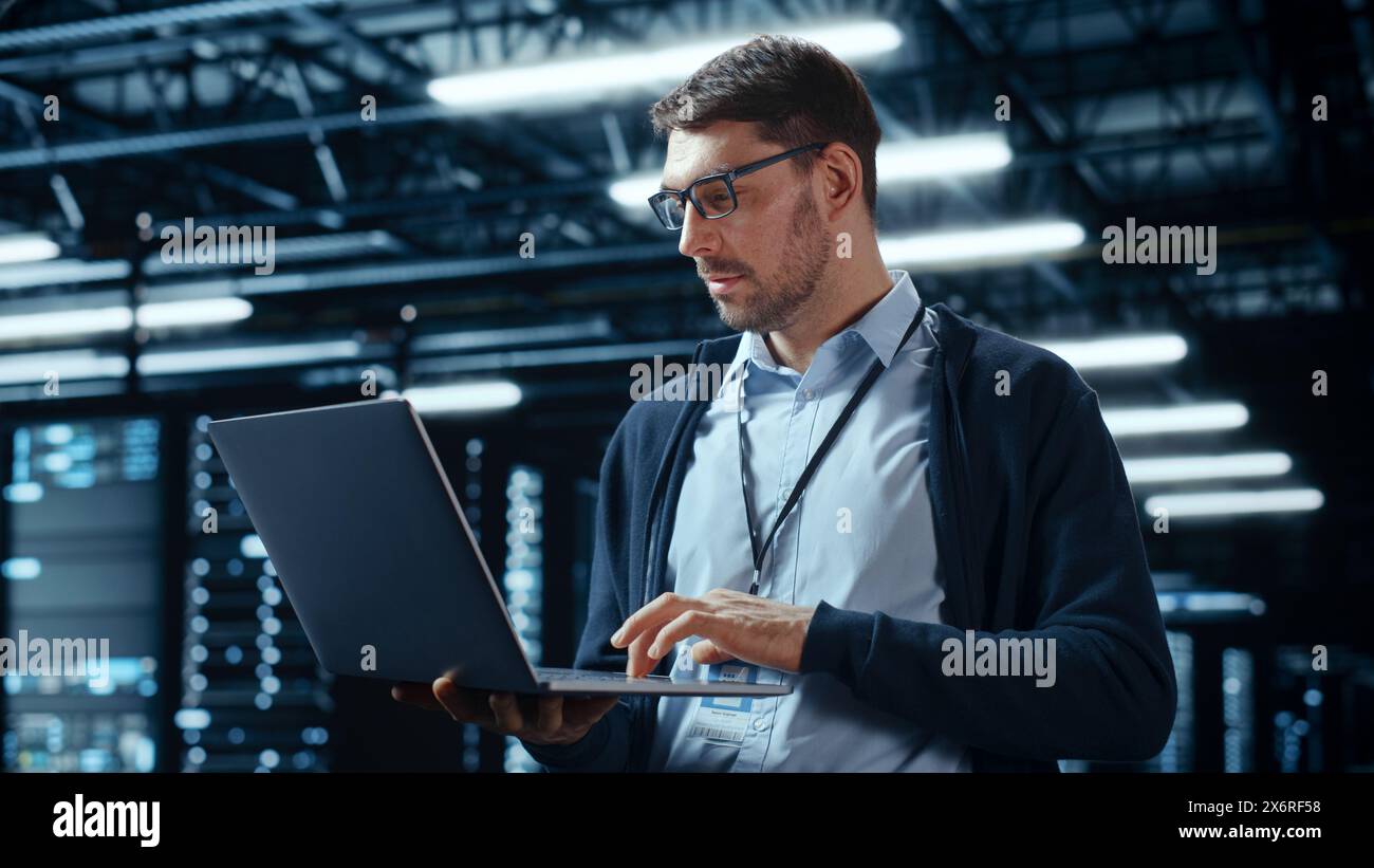 Successful Data Center IT Specialist Using Laptop Computer. Server Farm Cloud Computing Facility with System Administrator Working. Data Protection Engineering Network for Cyber Security. Stock Photo