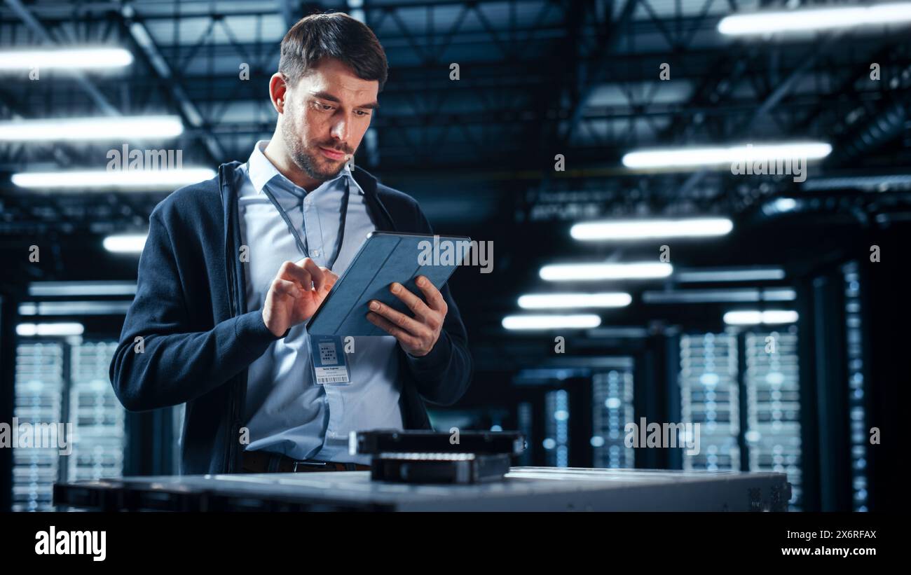 Successful Data Center IT Specialist Using Tablet Computer. Server Farm Cloud Computing Facility with System Administrator Working. Data Protection Engineering Network for Cyber Security. Stock Photo