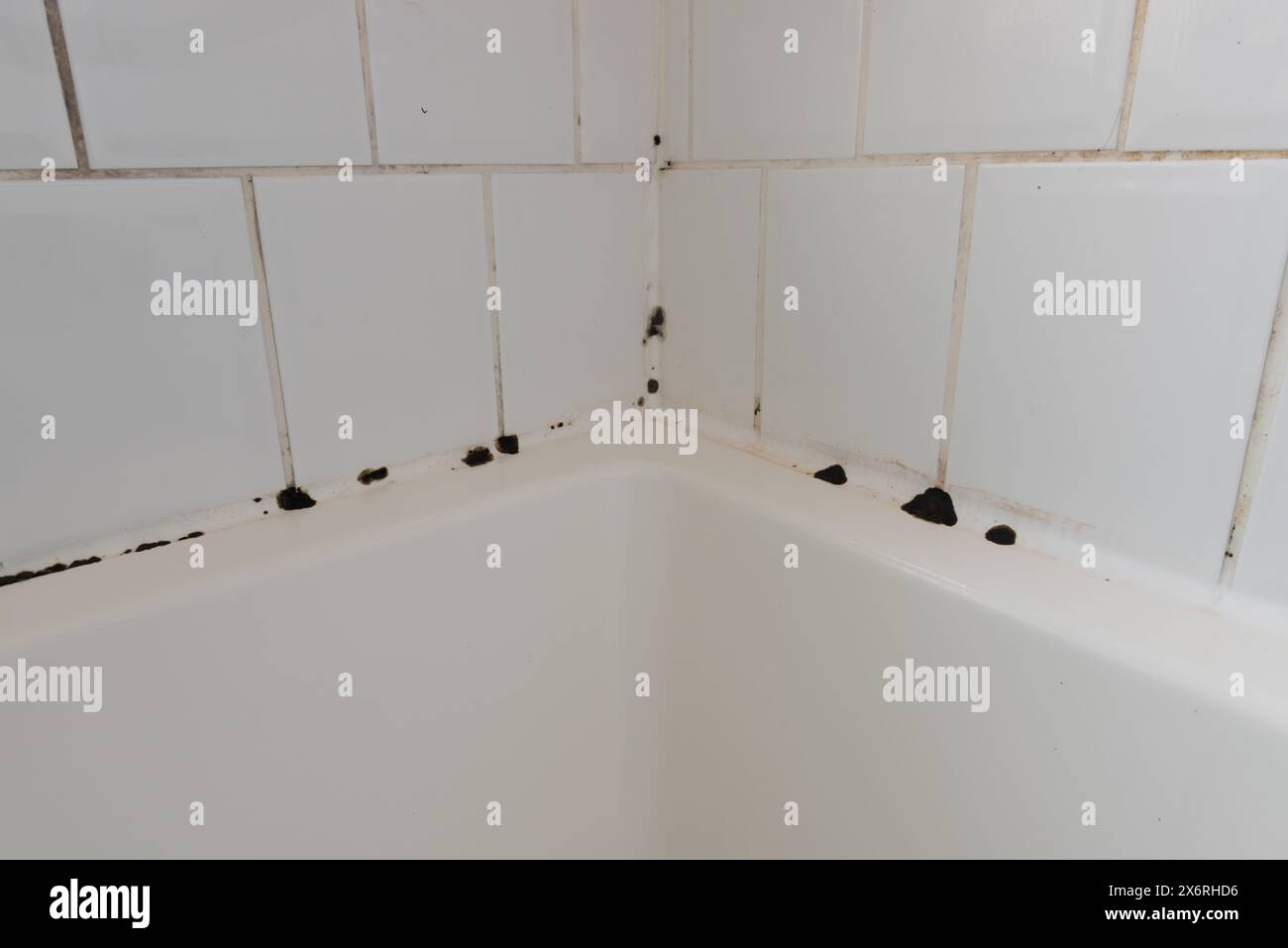 Cracked failing grout in bathroom shower and bath on white porcelain tiles with build up