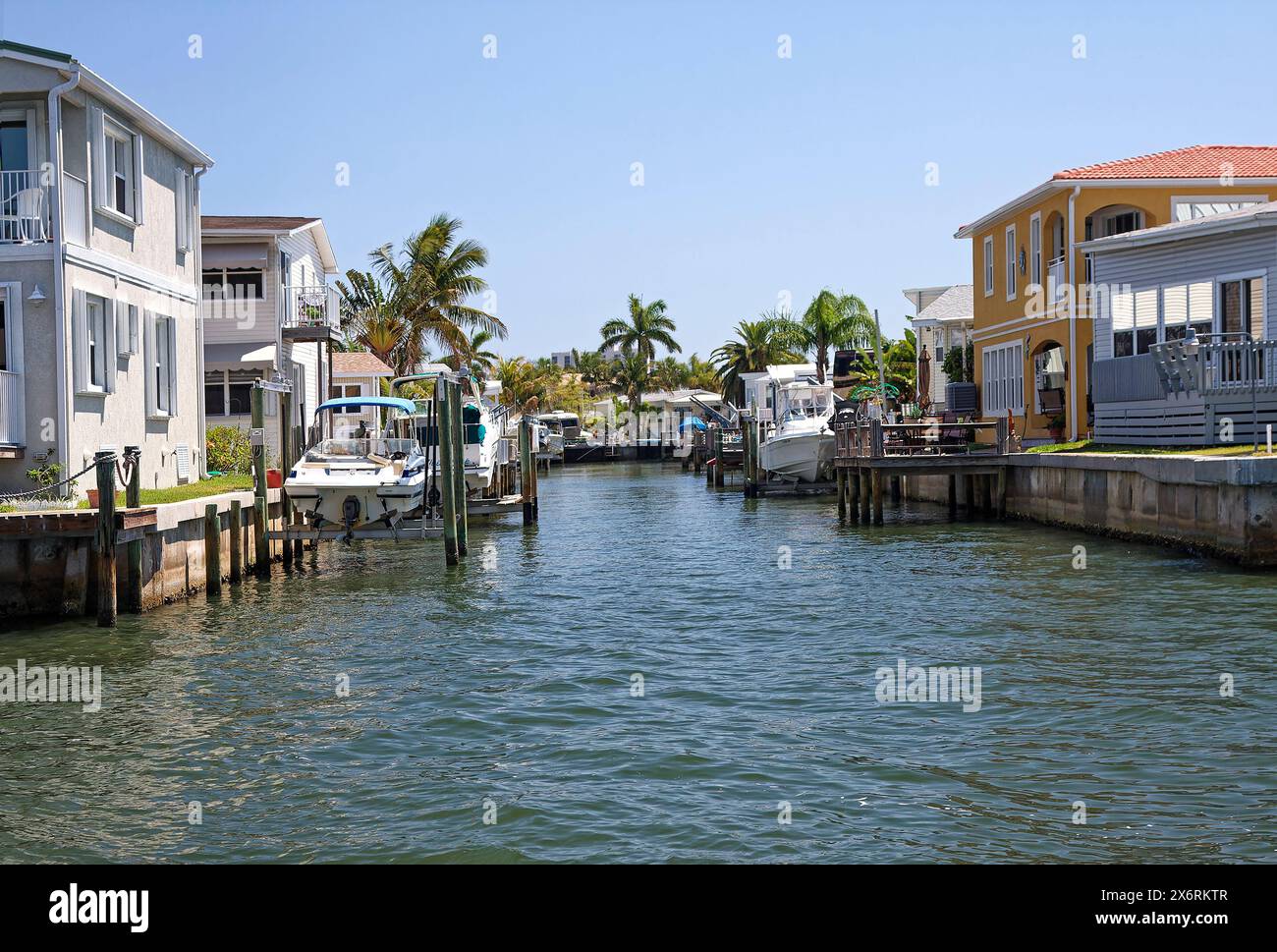 canal scene, narrow waterway, houses, close together, boats docked, on lifts, out of water, palm trees, spring, Florida Stock Photo
