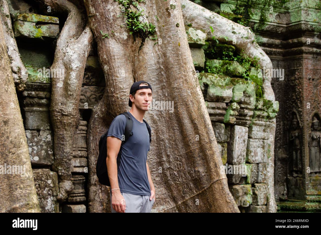 Caucasian Tourist in Front of The Big Trunk And Roots Of a Giant Tree in Ta Prohm, Angkor Wat, Siem Reap, Cambodia Stock Photo