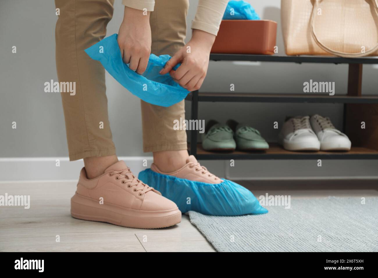 Woman Wearing Blue Shoe Covers Onto Her Sneakers Indoors Closeup Stock