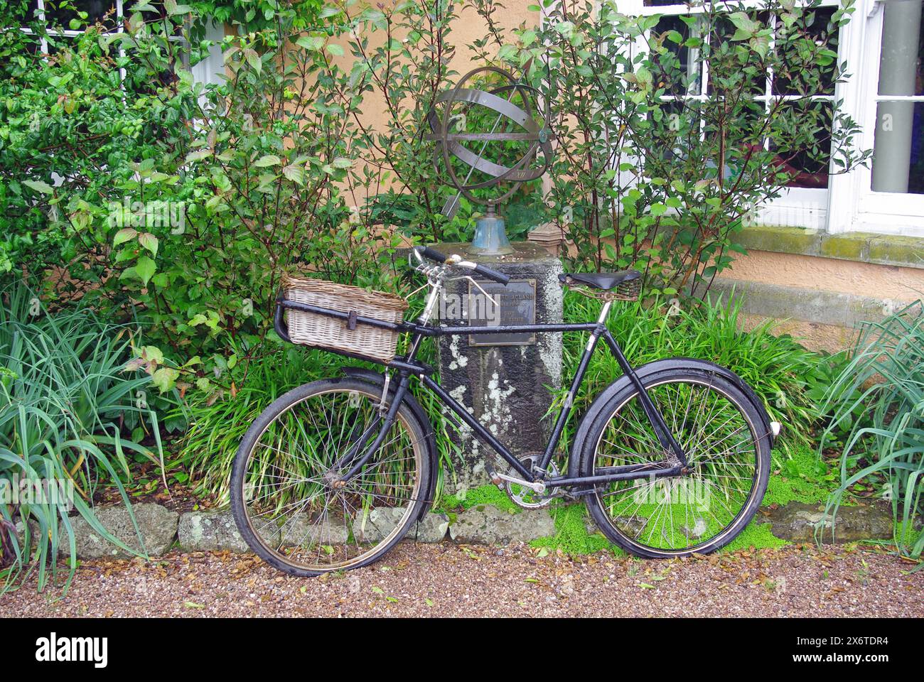 An old delivery bicycle leaning against an armillary sundial outside Killerton House, Exeter, Devon, England, UK, Europe Stock Photo