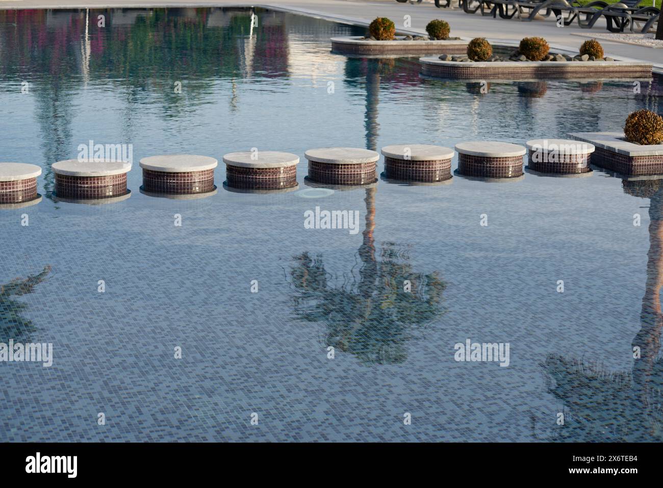 Reflections of palm trees in a swimming pool. An abstract representation of a relaxing holiday. Stock Photo