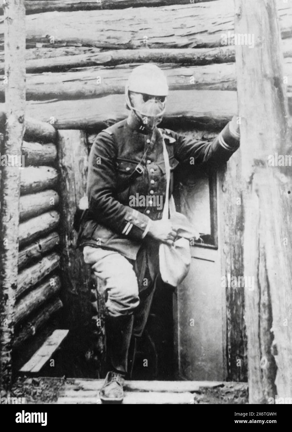 A photograph of a French bombing infantryman leaving his shelter in a trench, taken during the First World War, circa 1915. He is shown with a mask and a satchel, likely containing explosives. This image highlights the dangerous role of bombing infantrymen and the hazardous environment of trench warfare. Stock Photo