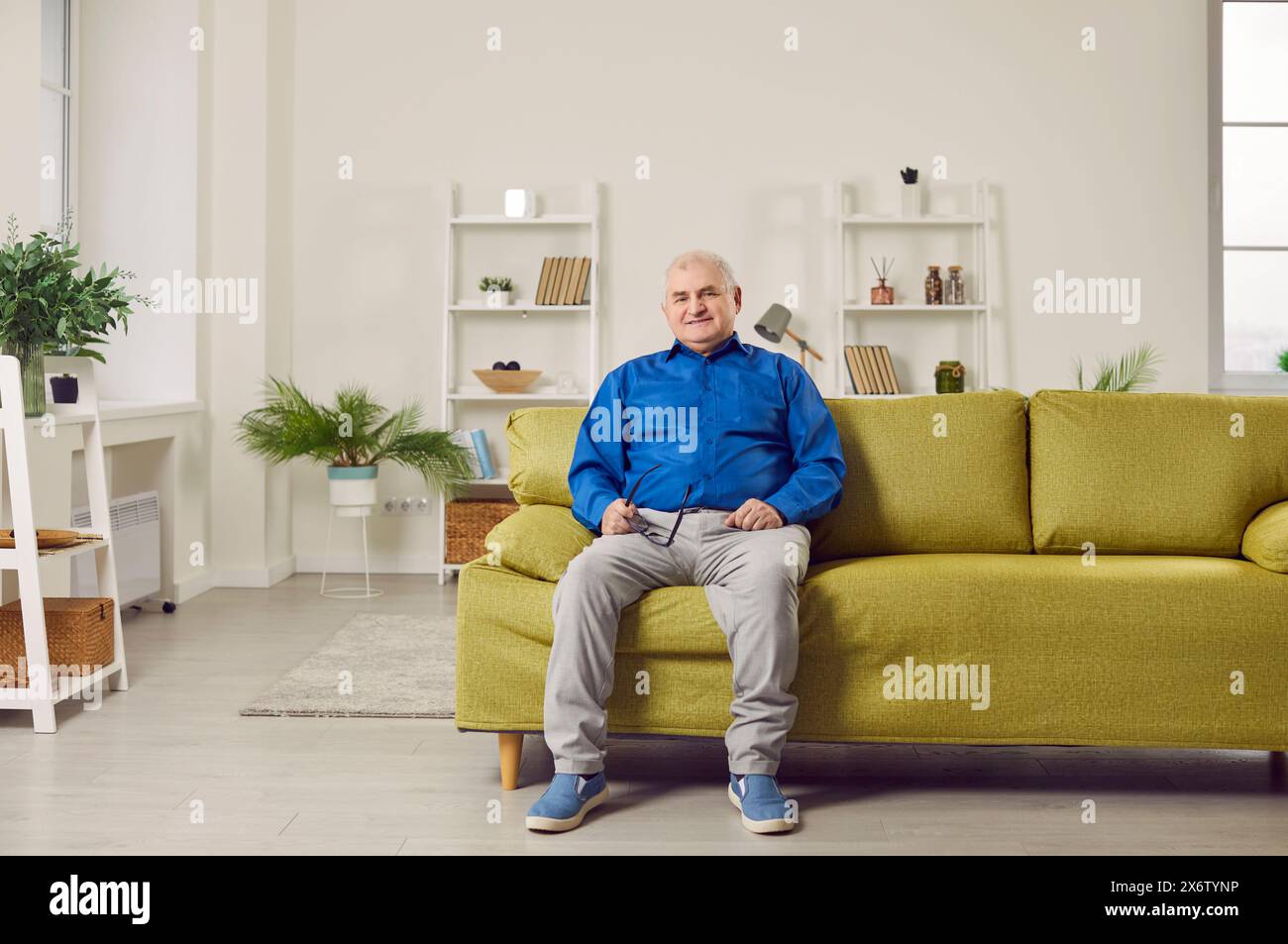 Optimistic elderly man sitting on sofa at home Stock Photo