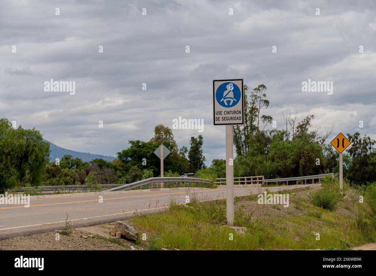 Mountain road. Road with road signs 'use seat belt', sign in Spanish. Safe travel driving Stock Photo