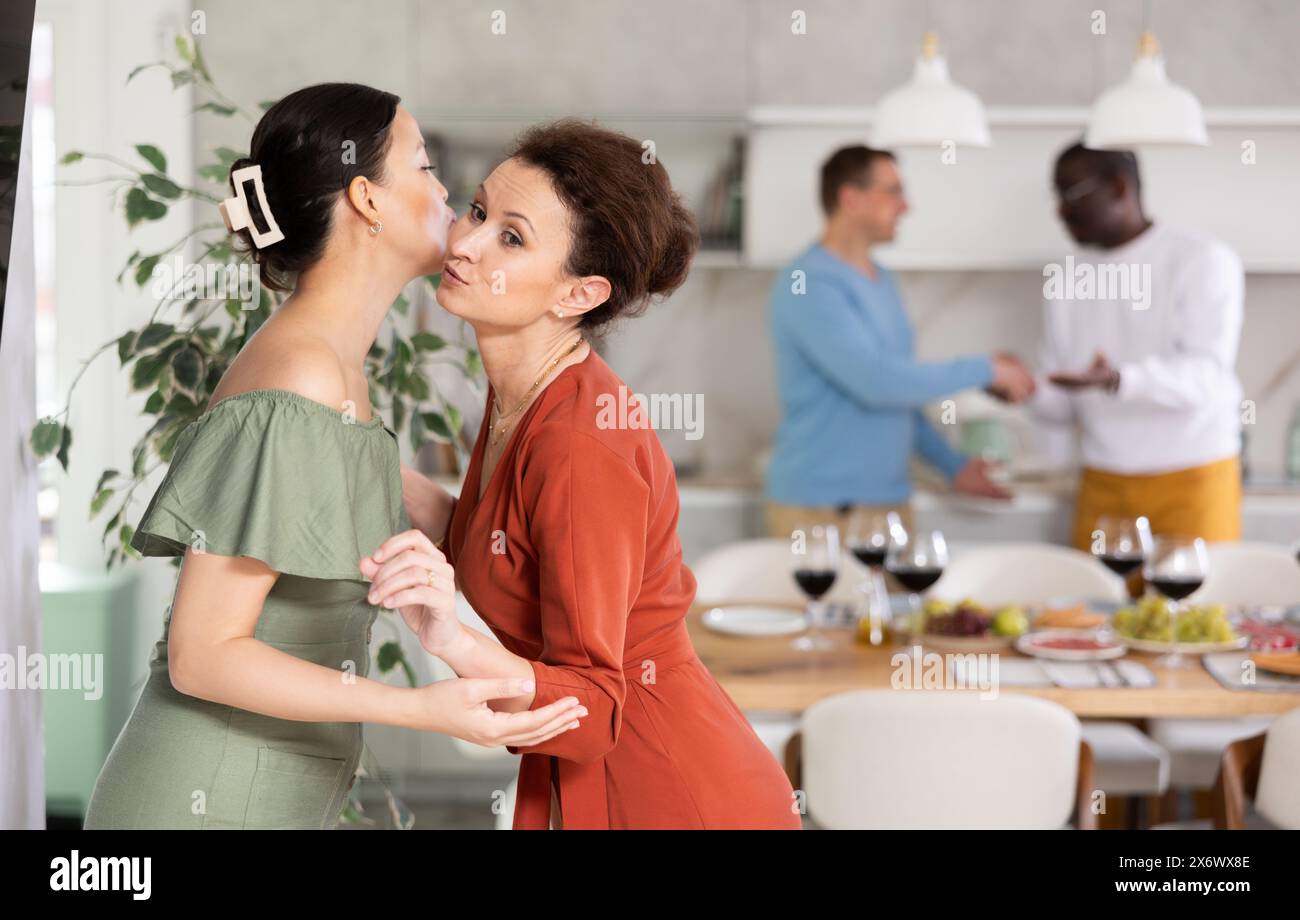 Smiling woman giving greeting kiss to bestie at dinner party Stock ...