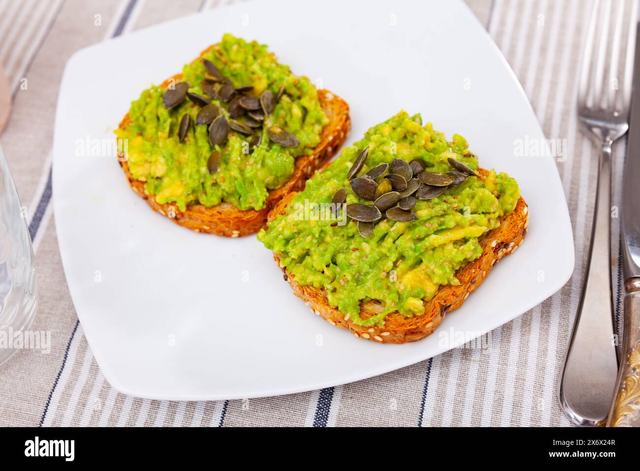 Fresh guacamole on toasted multigrain bread with pumpkin seeds Stock Photo