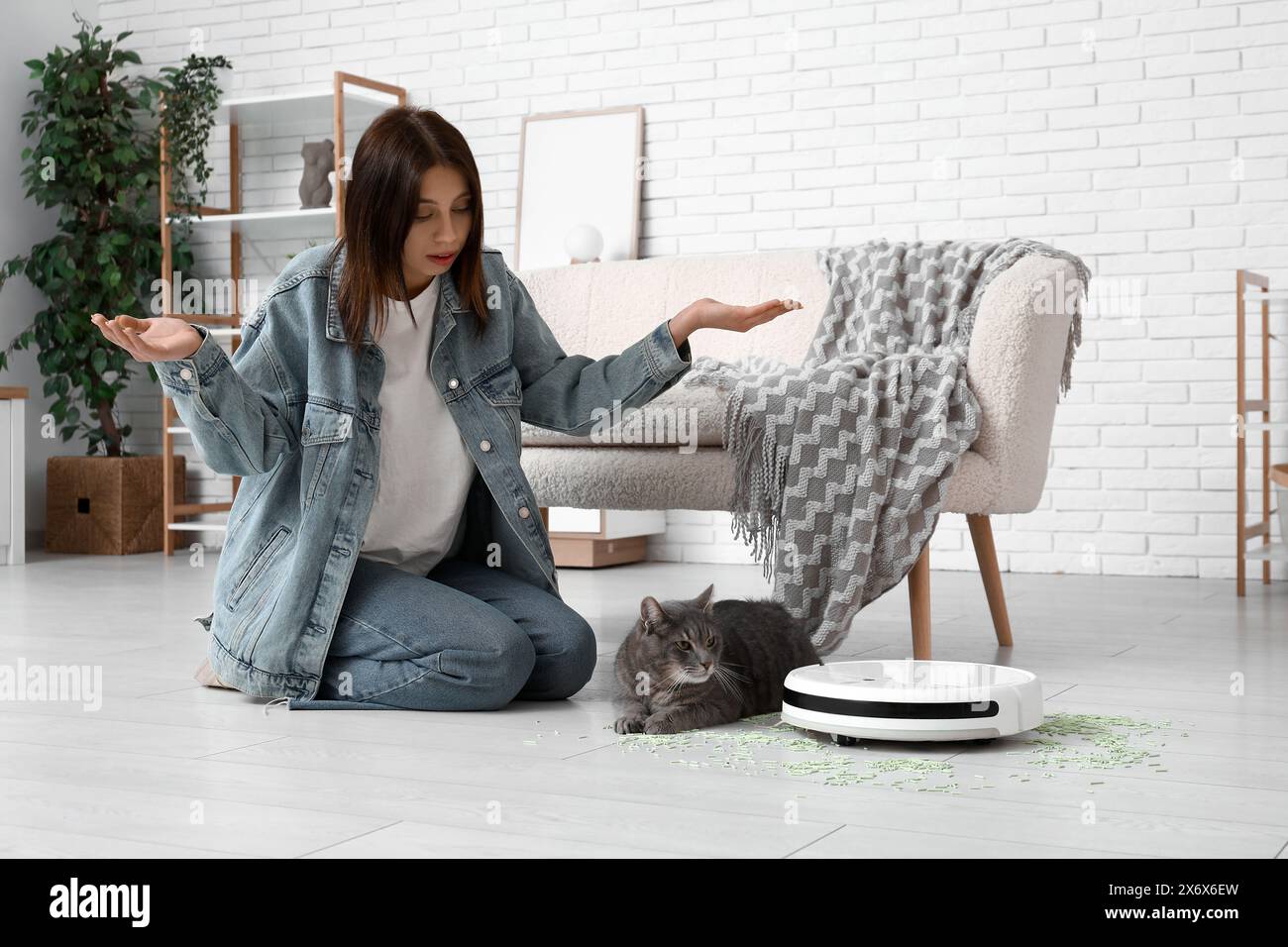 Emotional woman with cute cat, robot vacuum cleaner and scattered